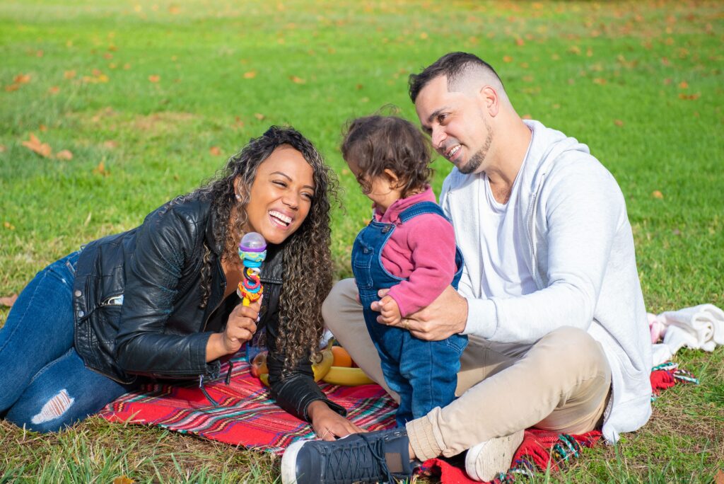 A joyful family enjoys quality time with their child outdoors on a sunny day.